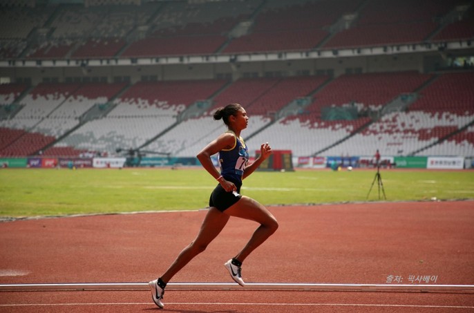 왼쪽에서 오르쪽으로 트랙을 달리는 여자 선수
